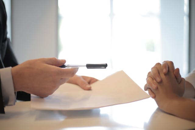 Person handing someone a contract and pen