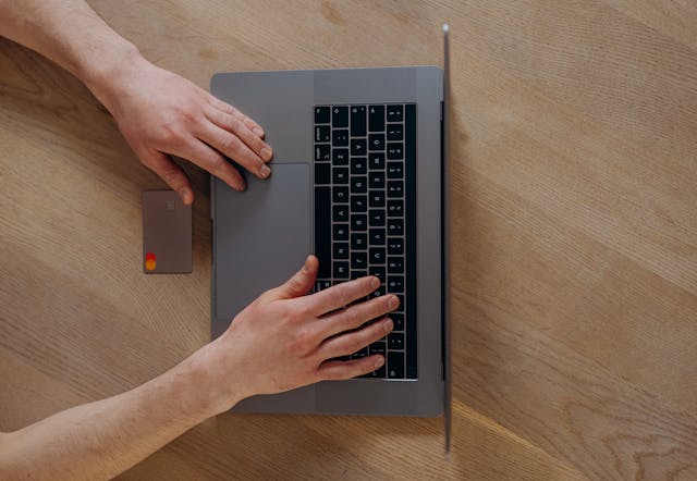 a person using a credit card and laptop to make an online payment