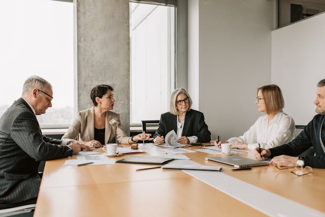 five people sitting in a conference room having a meeting