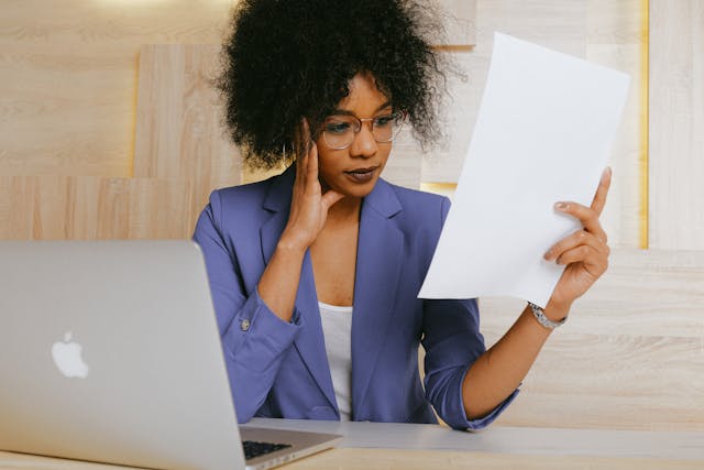 person in a blue blazer looking over documents at their desk