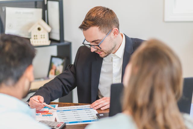 two people speaking with a real estate expert in their office