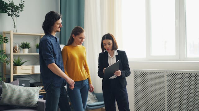 A landlord showing tenants information on a clipboard