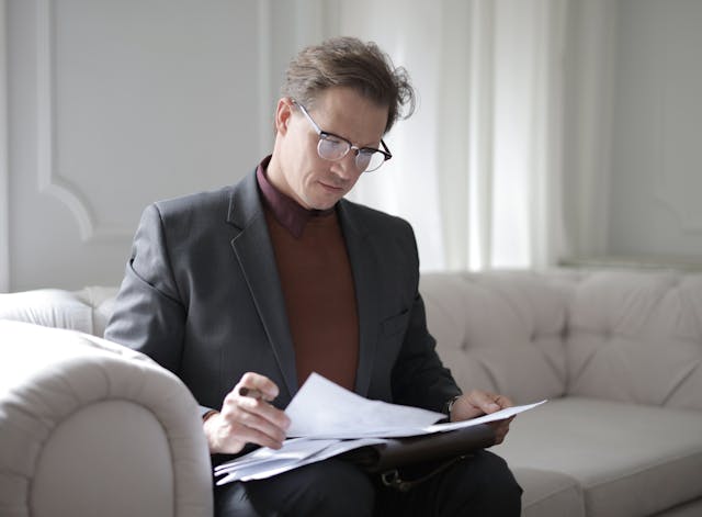 A person sitting on a couch reviewing contracts