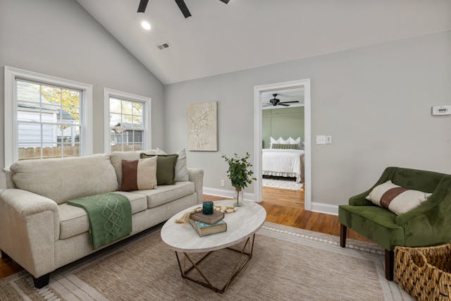 A white living room with a beige couch and green decor