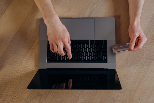 Person making an online payment with a credit card and laptop