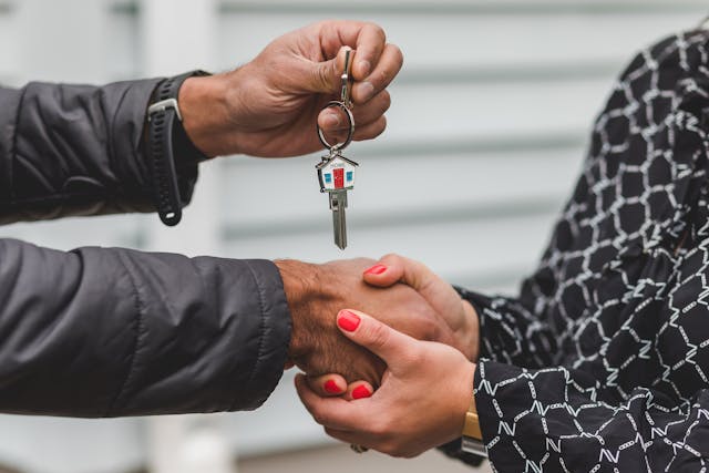 Two people shaking hands while exchanging house keys