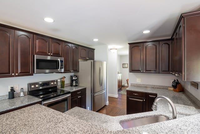 a kitchen with granite counters and dark wood cabinets