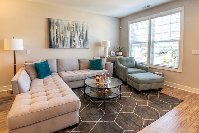 a living room with a beige L-shaped couch and blue lounge chair