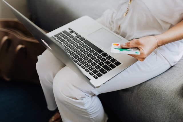 a person holding a credit card and their laptop to make an online payment
