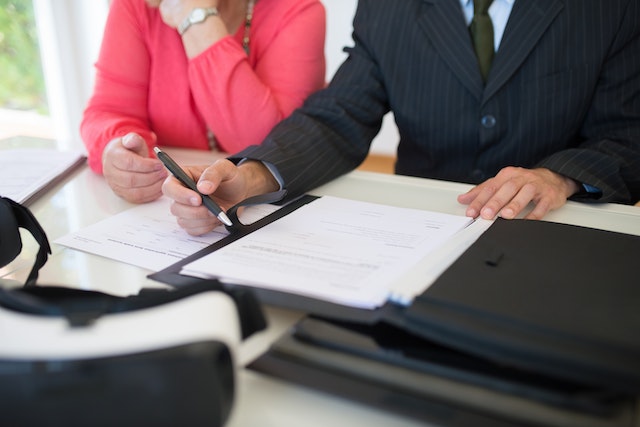 a person in a bright pink top and someone in a suit signing a rental agreement