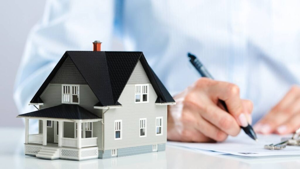 a person working on a document with a house figurine next to them